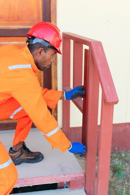 black-male-carpenter-taking-measurements-outside-house-repairing-house_531091-1211